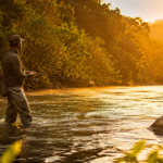 Pescador praticando pesca esportiva em rio brasileiro ao entardecer